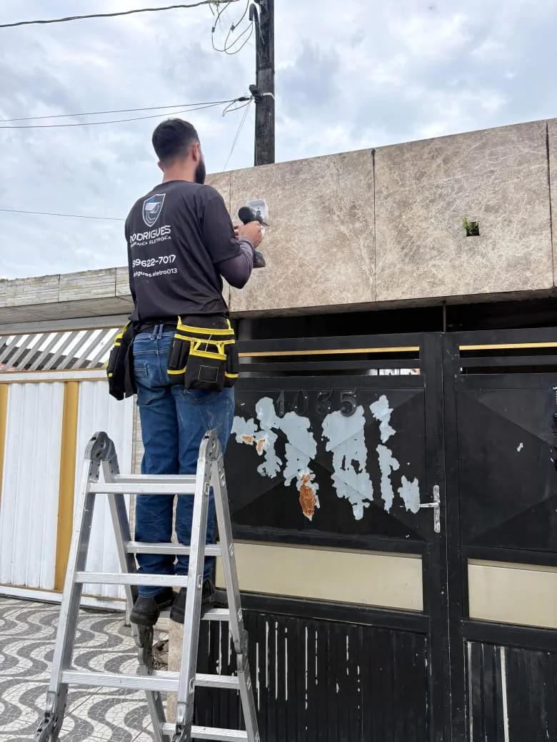 Técnico da Rodrigues instalando câmera na fachada de residência em Santos